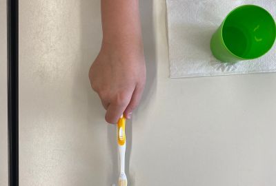 Ein Kind hält eine Zahnbürste in der Hand.