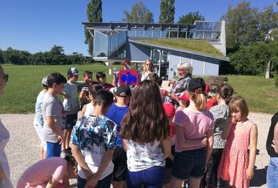 Zu sehen sind Schüler die draußen vor einer Wiese im Pulk stehen