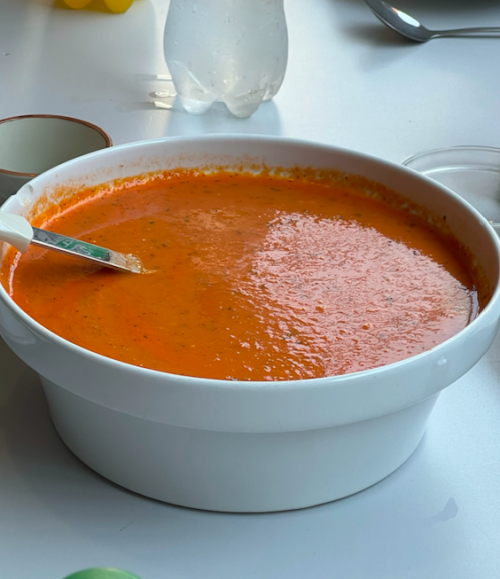Eine Schale mit Tomatensuppe steht auf dem Tisch.