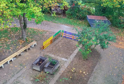 Der Schulgarten nach der Verschönerungsaktion mit geschnittenen Hecken, restauriertem Insektenhotel, buntem Zaun und einer neuen Sitzbank.