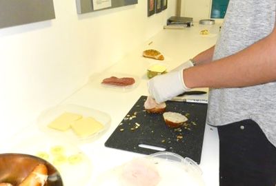 Zu sehen ist wie ein Schüler ein Brötchen belegt