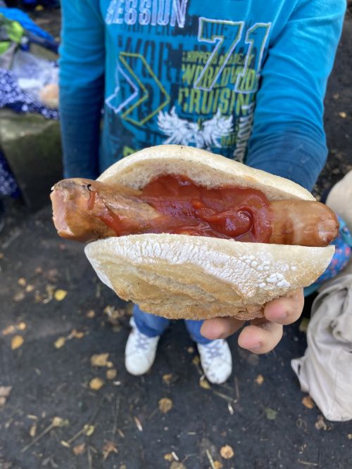 Kind zeigt ein Brötchen mit gegrillter Wurst