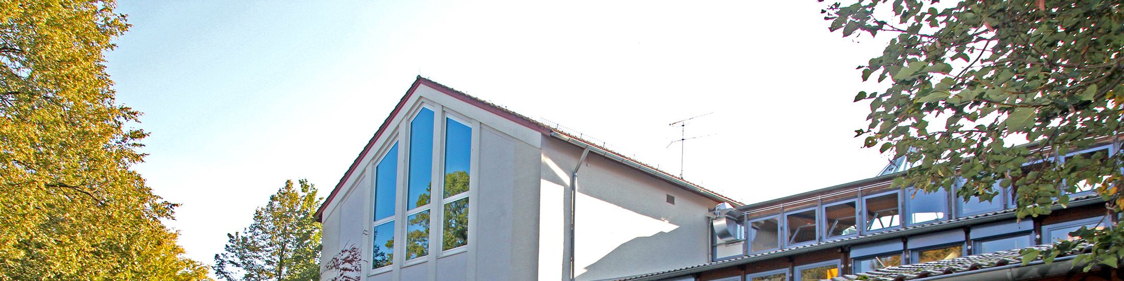 Zu sehen ist der das Schulhaus von hinten. Fenster mit blauen Rahmen