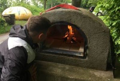 Ein Schüler schaut in den brennenden Pizzaofen