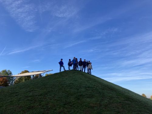 Zu sehen ist eine Gruppe aus Kindern auf einem Hügel mit blauem Himmel