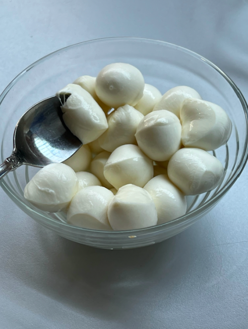 Eine Schale mit Mozzarella-Bällchen steht auf dem Tisch.